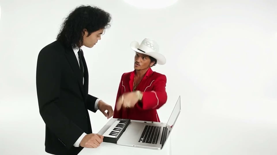 Ein Alors On Danse AI Video aus zwei Fotos: ein Bühnenkünstler im schwarzen Anzug am Keyboard und einer im roten Anzug mit weißem Hut, der am Laptop lacht